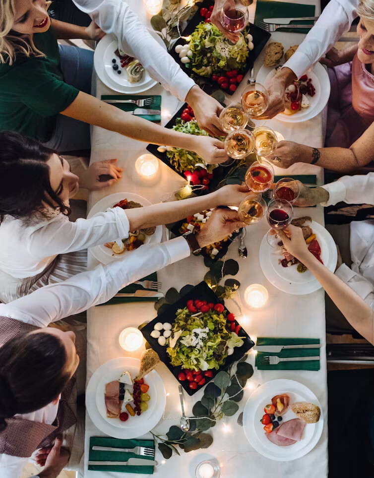 Friends toasting over a crowded dinner table, seen from above